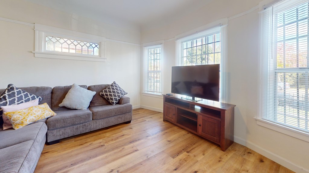A living room with a grey couch and a wooden cabinet.
