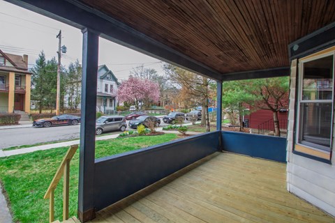 A wooden deck with a view of a street with cars and houses.