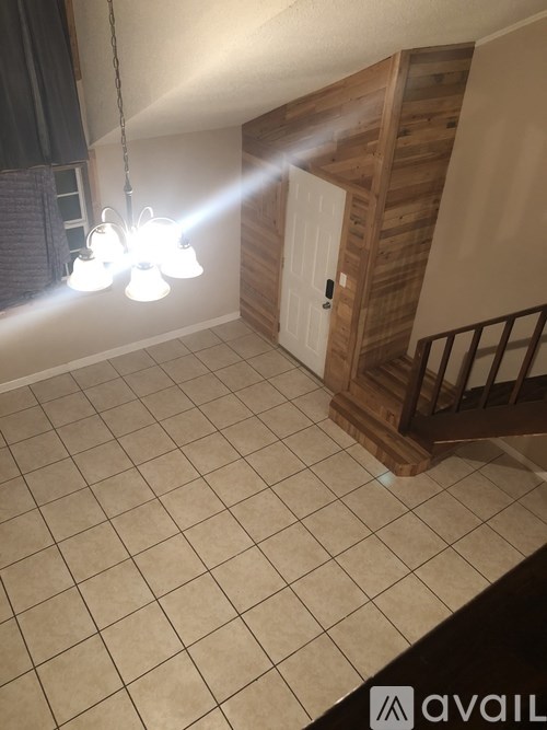 A room with a wooden staircase and a chandelier.