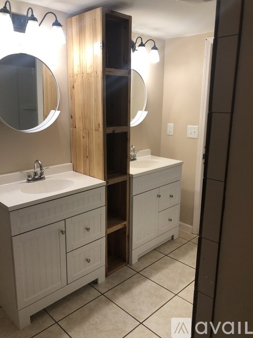 A bathroom with a white sink and a wooden cabinet.