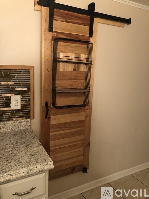 A wooden cabinet with a sliding door and a wire rack on top.