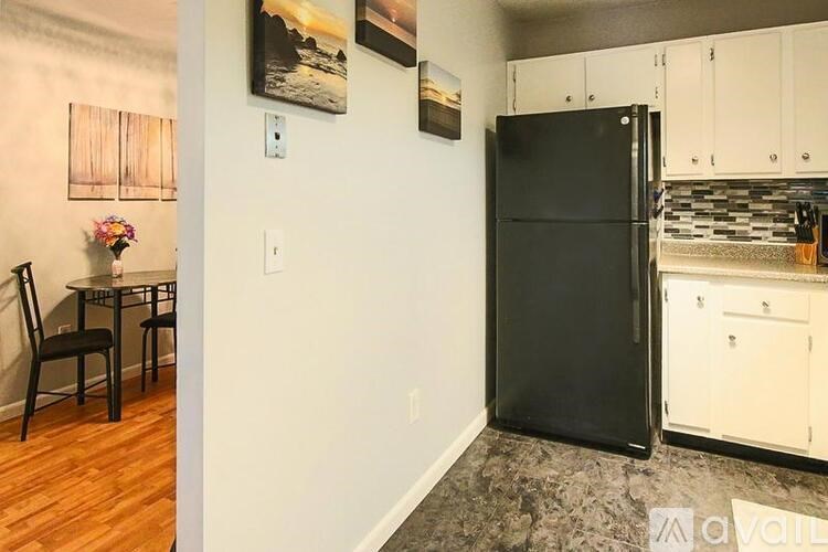 A kitchen with a black refrigerator and white cabinets.