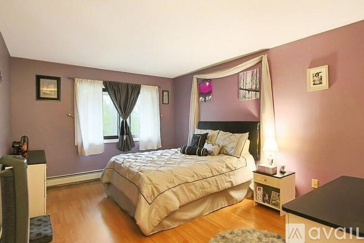 A bedroom with a bed, nightstand, and window.