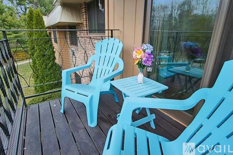 Two blue plastic chairs and a table on a deck.