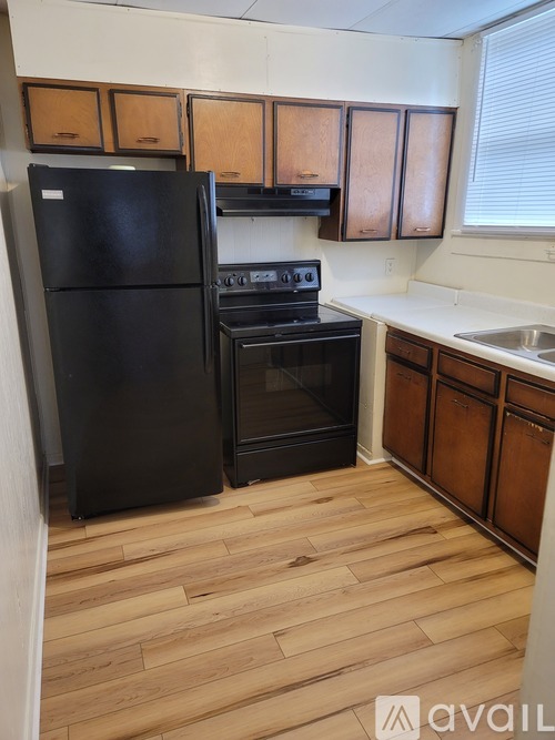 A kitchen with black appliances and wooden cabinets.