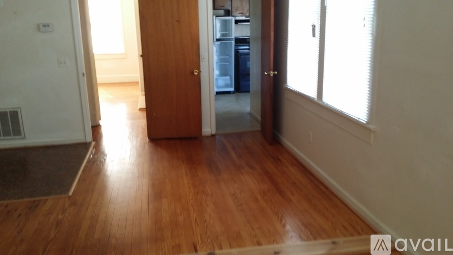 A room with wooden floors and a door leading to a kitchen.
