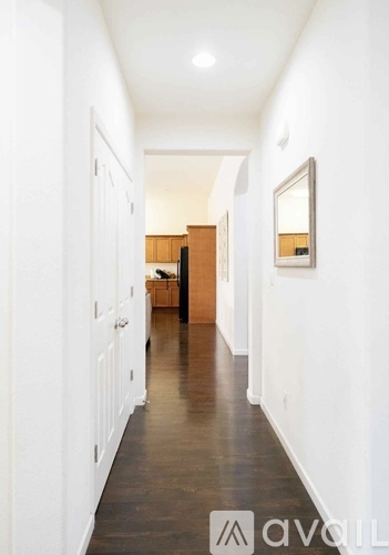 A long hallway with white walls and a wooden floor.