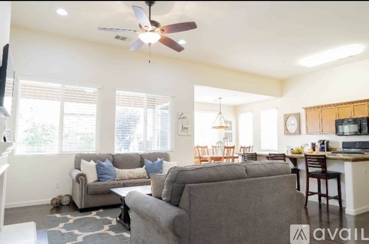 A living room with a grey couch and a fan on the ceiling.