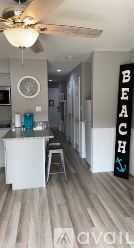 A kitchen with a white counter and a fan on the ceiling.