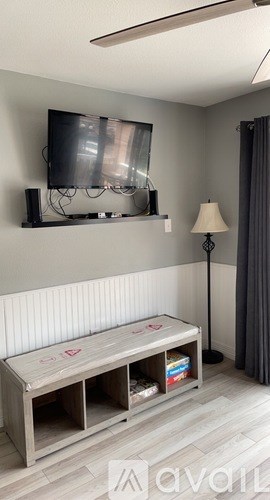 A modern living room with a television, a bench, and a lamp.