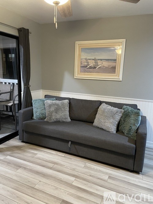 A grey couch with pillows and a painting on the wall.