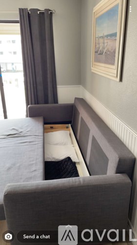 A grey couch with a pillow and a blanket on it.