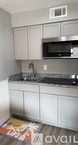 A kitchen with white cabinets and a black microwave.