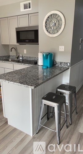 A kitchen with a granite countertop and two stools.