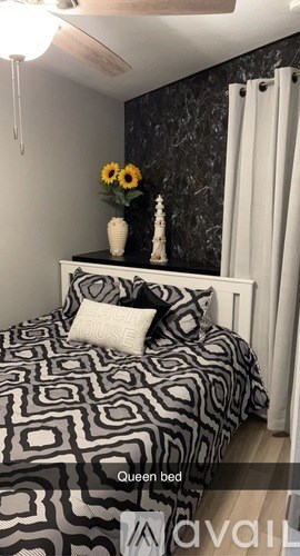 A queen bed with a black and white comforter and pillows.