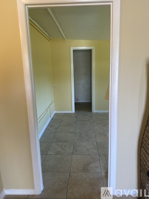A hallway with a tiled floor and a door at the end.