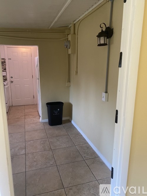 A hallway with a trash can and a door.