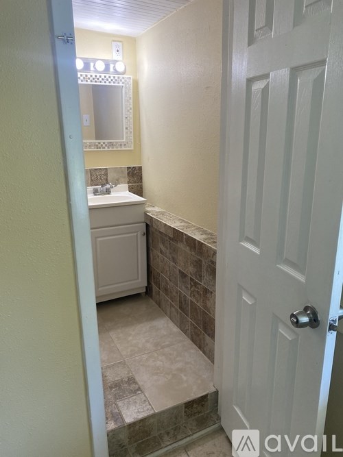 A bathroom with a white door and a mirror above the sink.