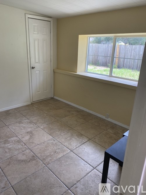 A room with a tiled floor and a window overlooking a fence.