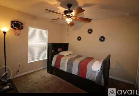 A bedroom with a bed, a ceiling fan, and a basketball hoop on the wall.