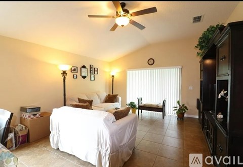 A bedroom with a white bed and a ceiling fan.