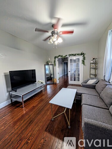 A living room with a television, couch, and a ceiling fan.
