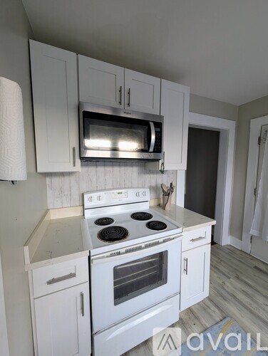 A kitchen with white cabinets and a stove top oven.