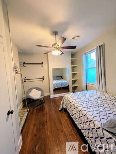 A bedroom with a bed, a chair, and a fan.