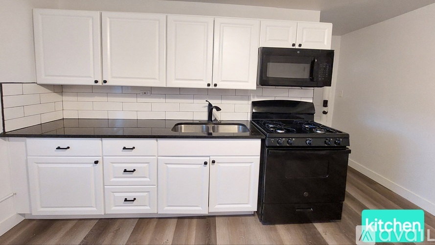 A kitchen with white cabinets and black appliances.
