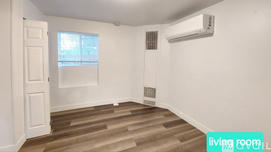 A living room with a wooden floor and a window.