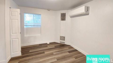 A living room with a wooden floor and a window.