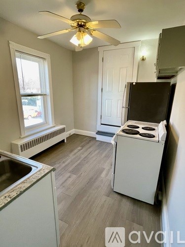 A kitchen with a white stove and a window with blinds.