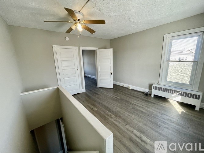 A room with a ceiling fan and a window with a view of a fence.