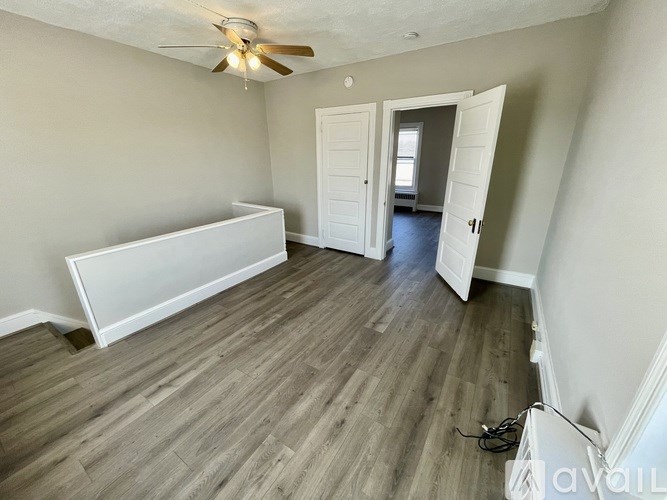 A room with a white bed and wood flooring.