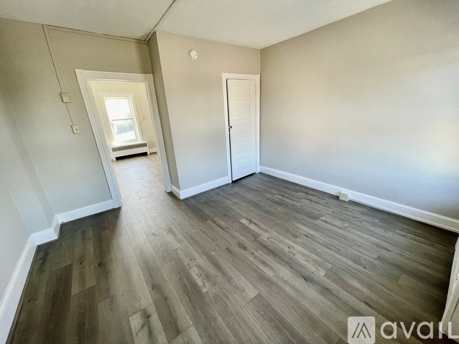 A room with wooden flooring and a door on the right side.