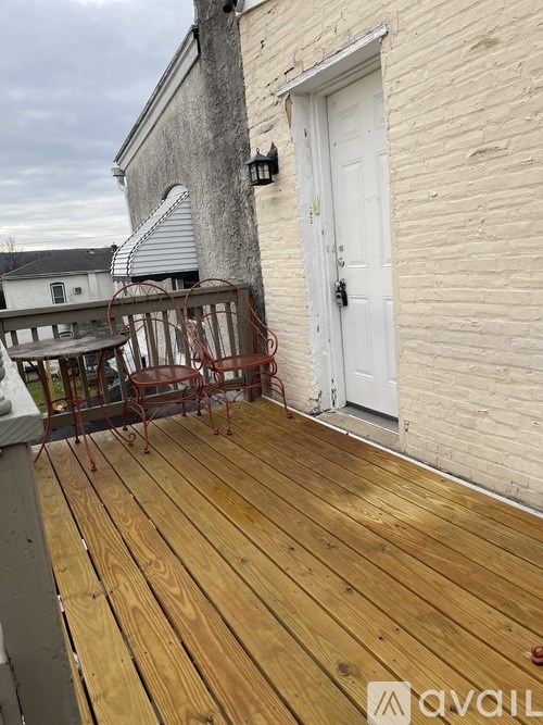 A wooden deck with a white door and a table and chairs.