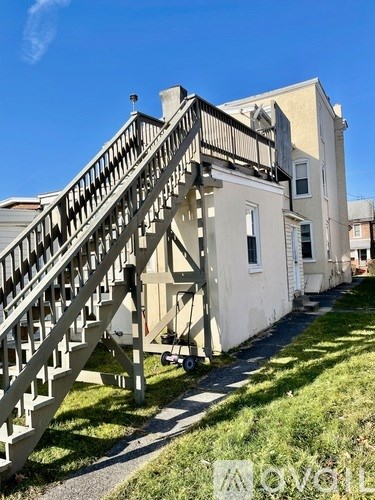 A white building with a wooden staircase leading to the second floor.