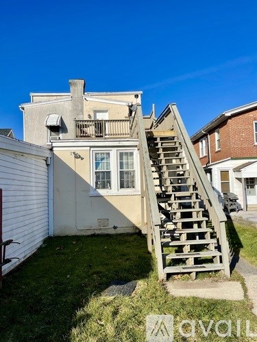 A wooden staircase leads up to a window on a house.