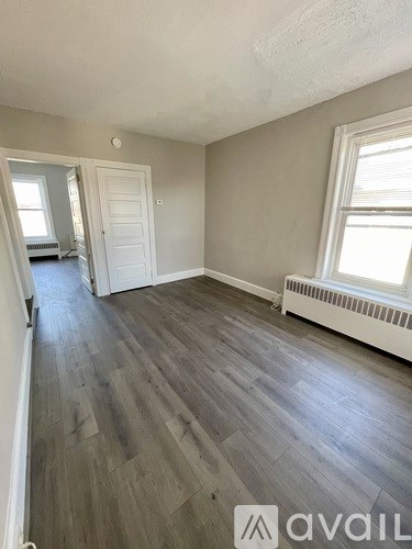 A room with grey flooring and a window with white blinds.