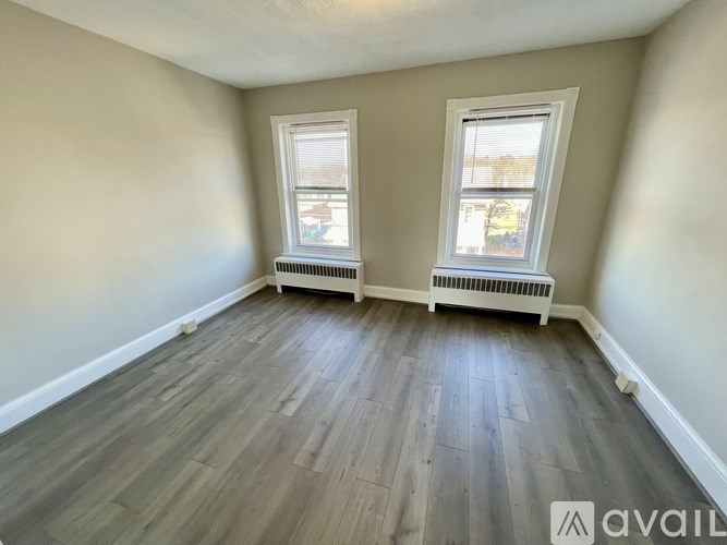 A room with two windows and a radiator on the wall.