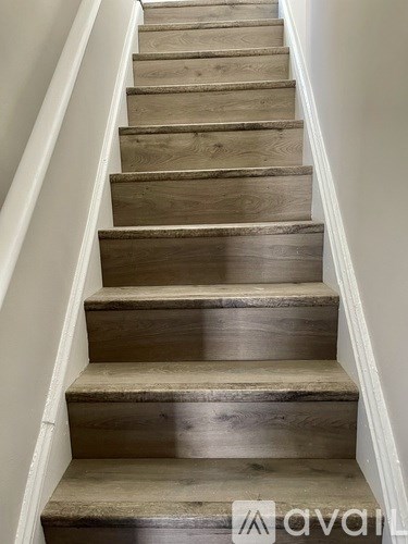 A set of wooden stairs with a white railing.