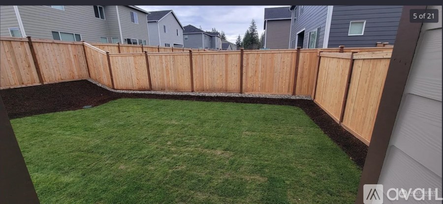 A backyard with a wooden fence and a green lawn.