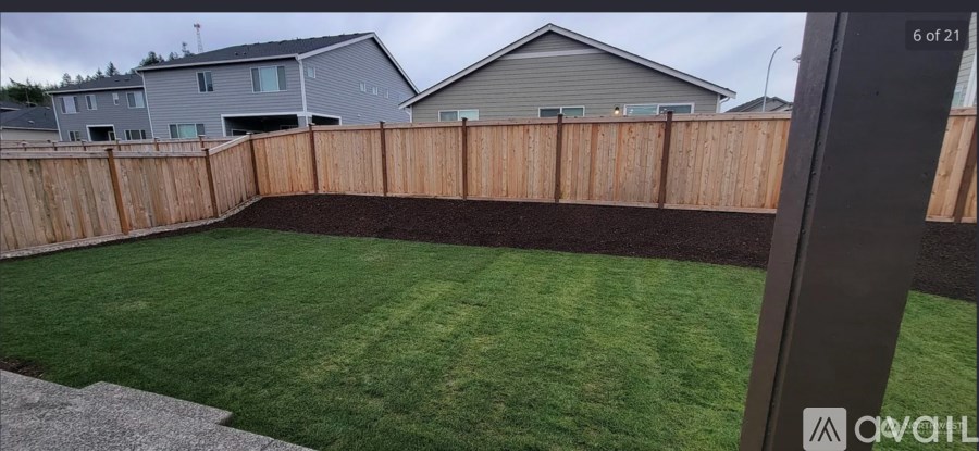 A backyard with a wooden fence and a green lawn.