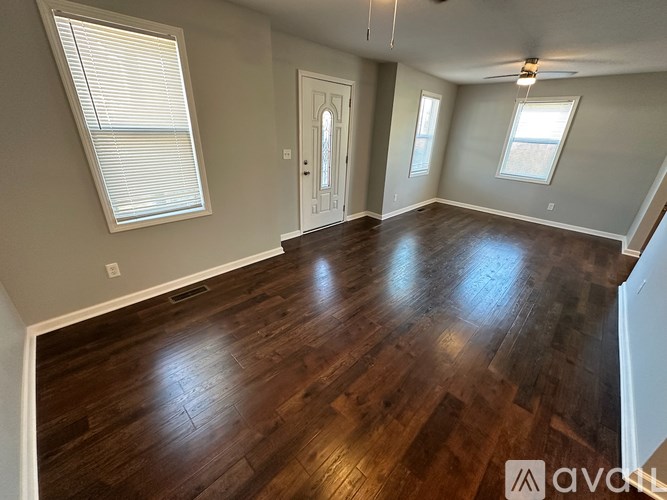 A room with wooden floors and a window with blinds.