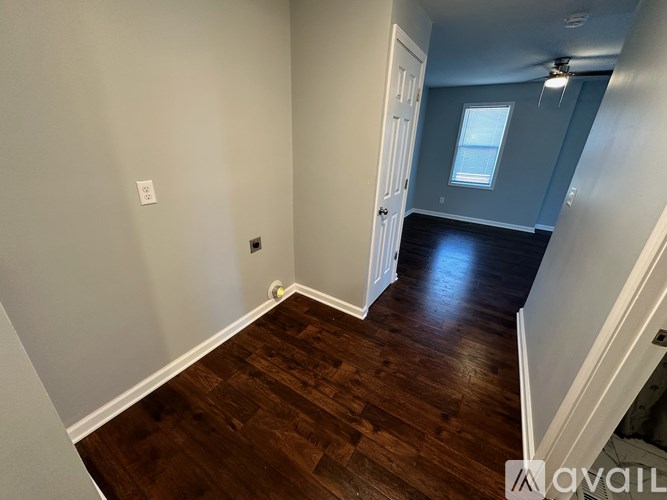 A room with wood flooring and a window in the distance.