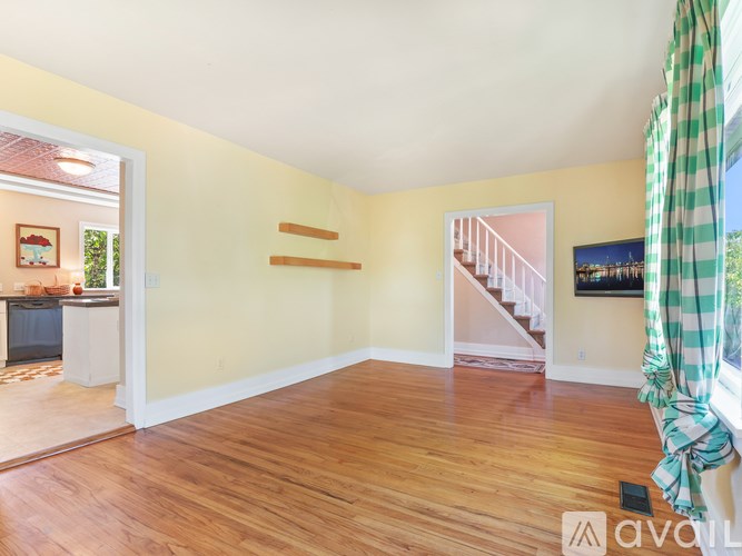 A room with wooden floors and a staircase in the background.
