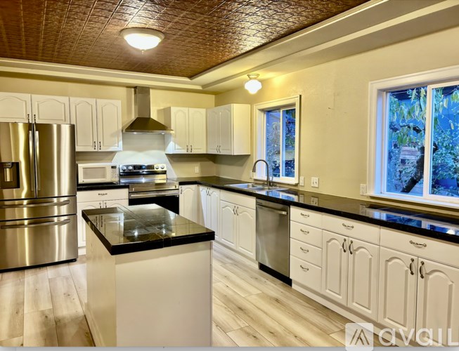 A kitchen with white cabinets and a black countertop.