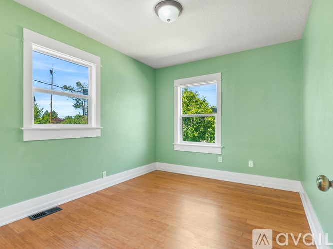 A room with two windows and wooden flooring.