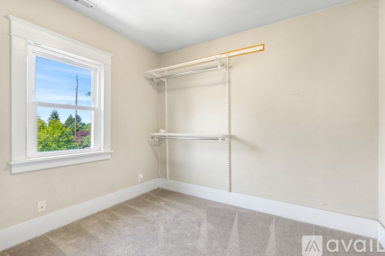 A room with a window and a clothes rack.