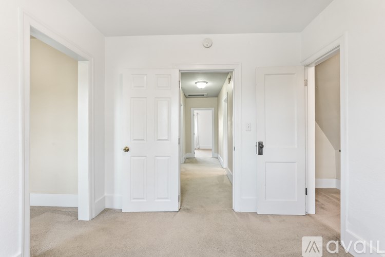 A hallway with white doors and carpeted floors.